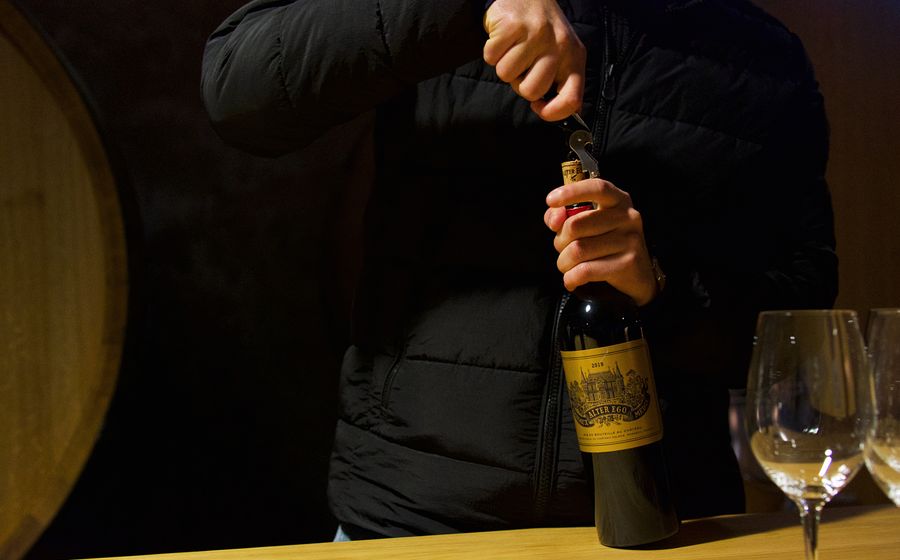 Un visiteur débouche une bouteille de vin de Bordeaux lors d'une dégustation en cave