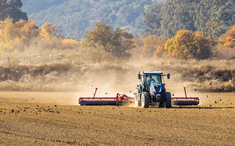 Tracteur avec semoir travaillant un champ labouré en fin de journée d'automne